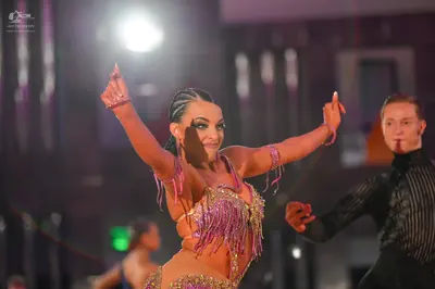 Dancesport competitor: Female dancer: gold and pink latin costume with heavy sequin embellishments and 