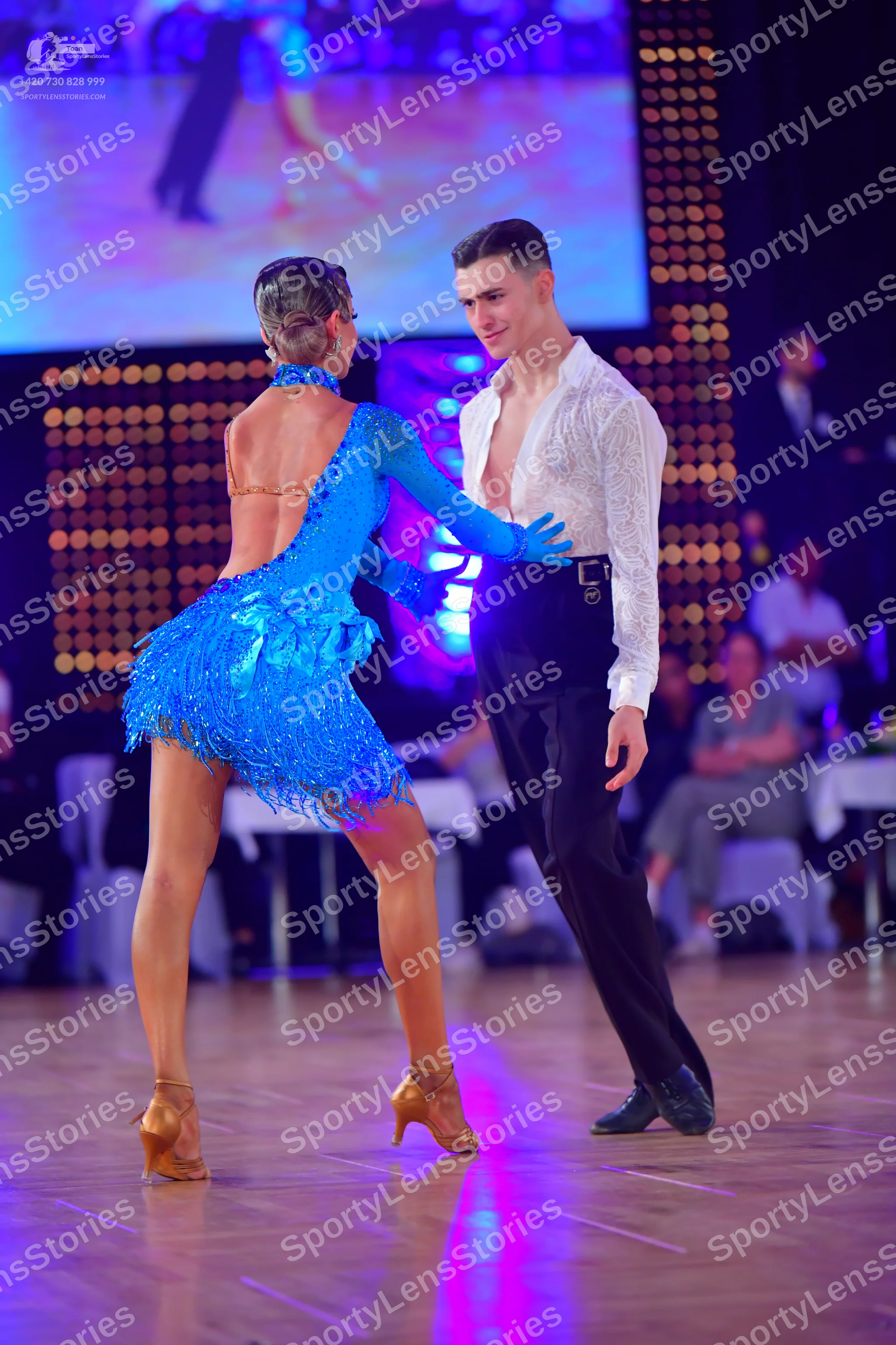 Dancesport competitor: Female dancer: blue sequined latin dress with fringe and long sleeves