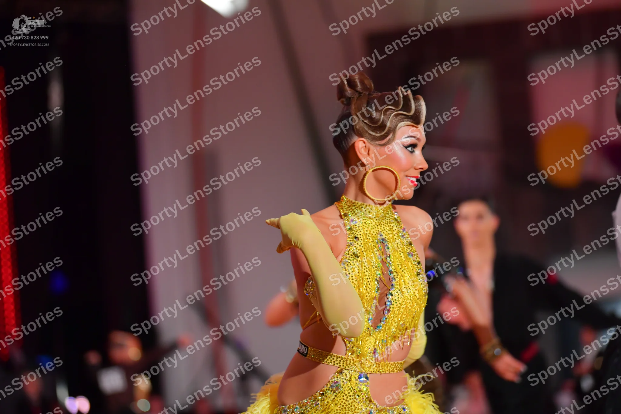 Dancesport competitor: Female dancer: yellow/gold Latin dance dress with sequins, fringe, and cutouts, 