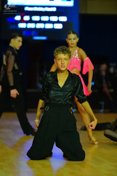 Dancesport competitor: Male dancer: black satin shirt with long sleeves and black wide-leg trousers wit