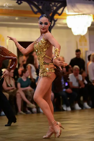 Dancesport competitor: Female dancer: gold Latin dance costume, heavily embellished with sequins and cr
