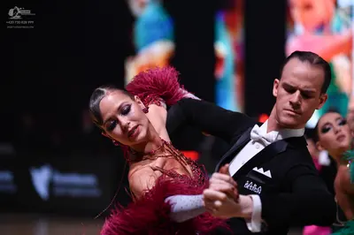 Dancesport competitor: Male dancer: black suit with white embroidery on the chest, white shirt, and whi