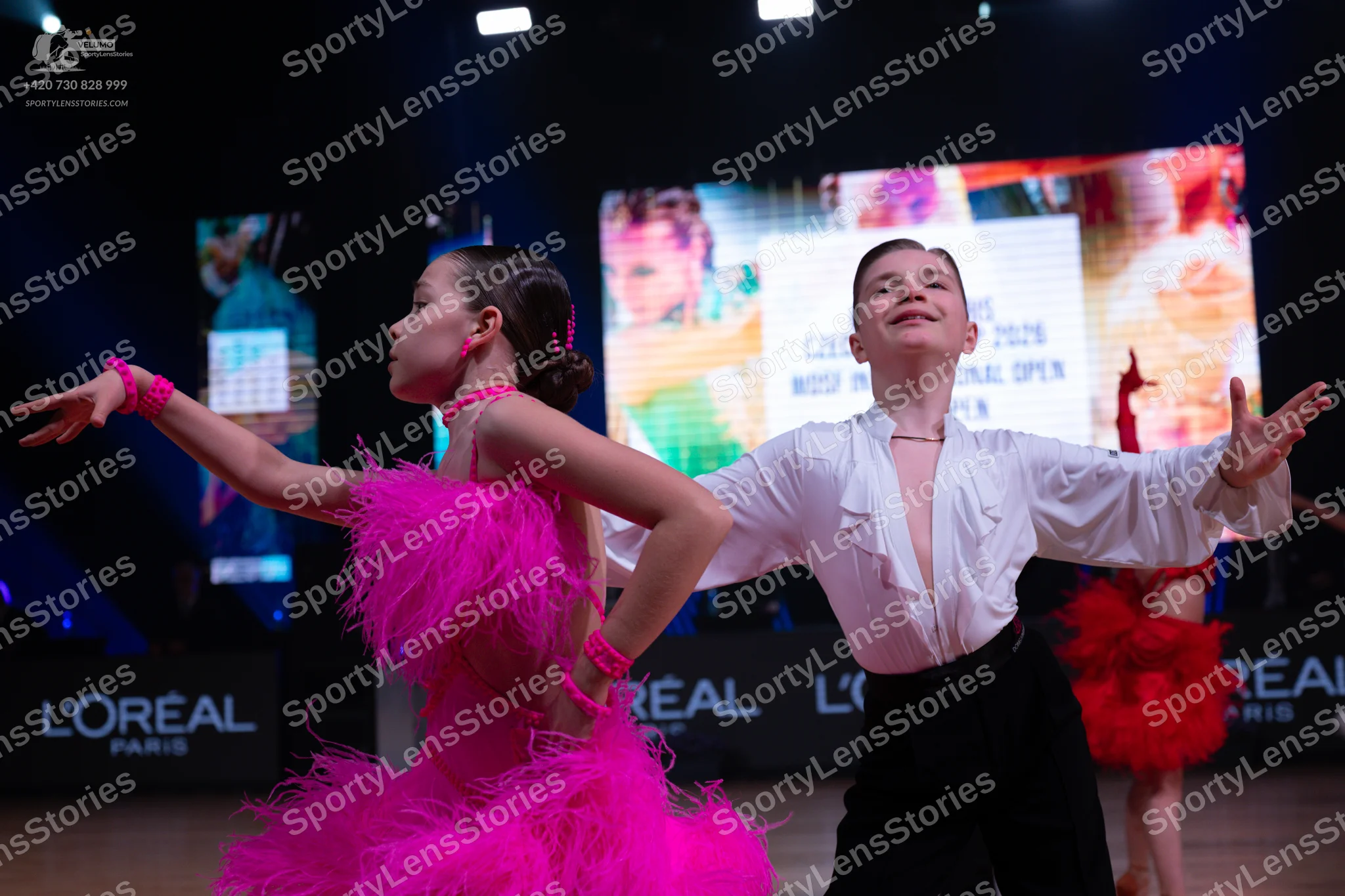 Dancesport competitor: Female dancer: pink Latin dress with large pink feathers and matching pink wrist