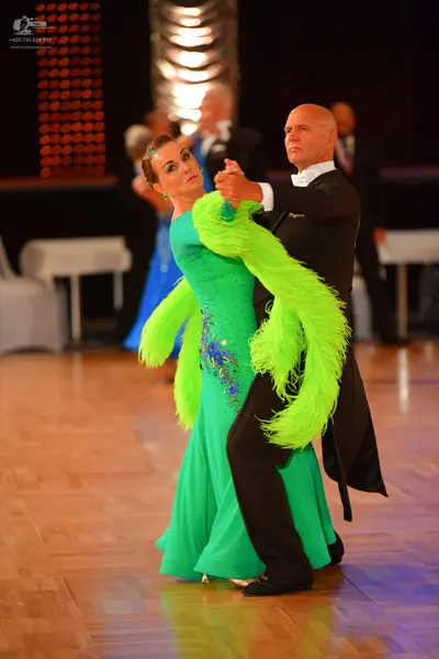 Dancesport competitor: Female dancer: bright green long ballgown with blue sequin embellishments and la