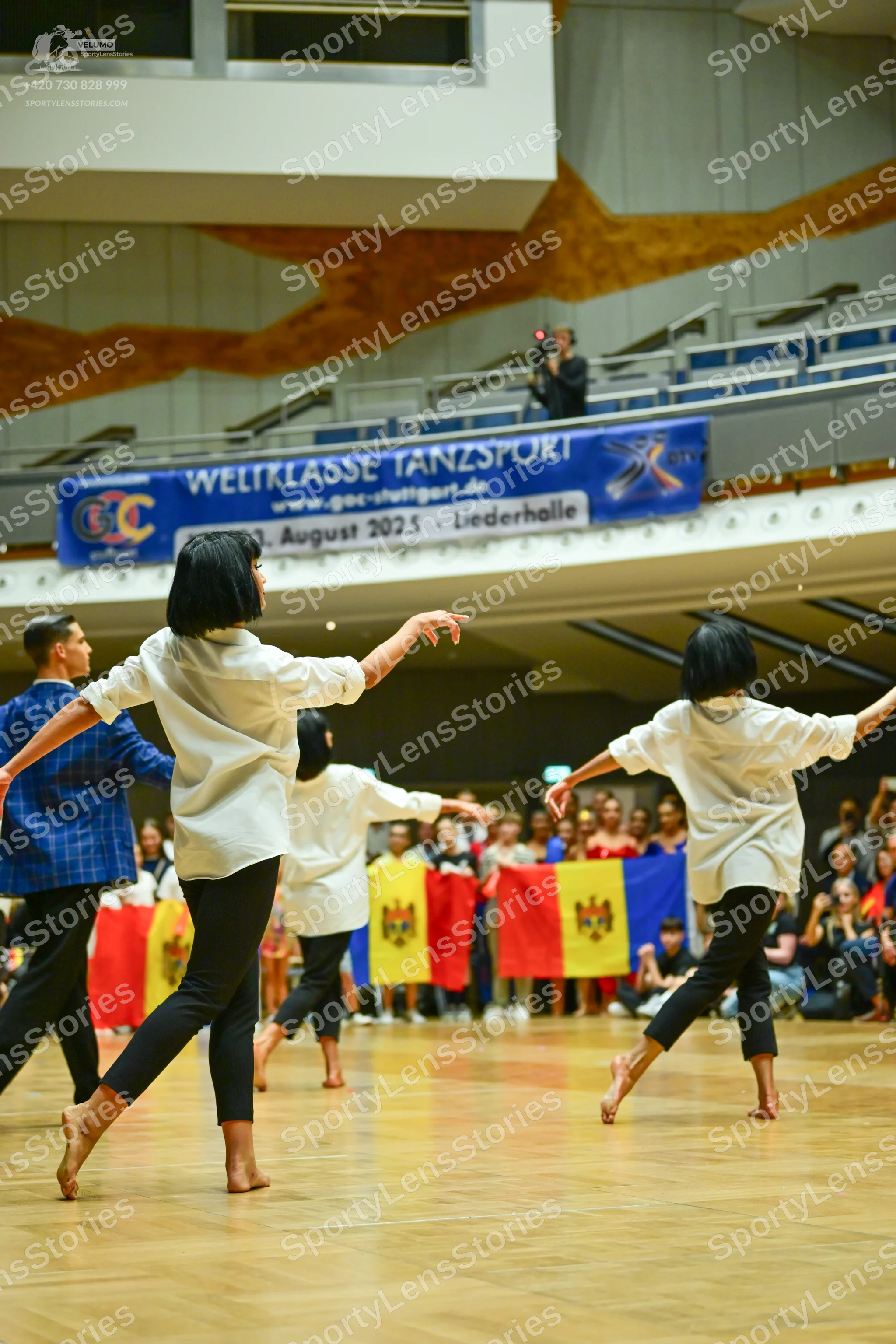 Dancesport competitor: Three dancers in the foreground are wearing white long-sleeved button-up shirts