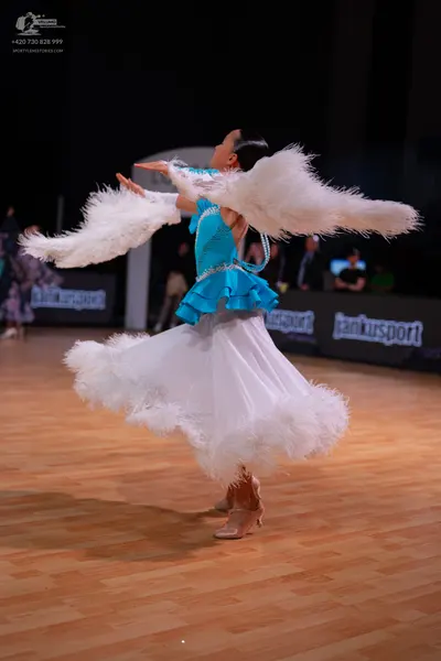 Dancesport competitor: Female dancer: turquoise bodice with a ruffled hem and a voluminous white skirt 