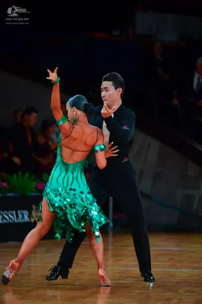 Dancesport competitor: Female dancer: green Latin dance dress with large sequins, featuring an open bac