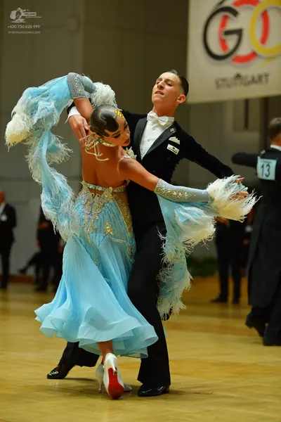 Dancesport competitor: Female dancer: light blue ballroom dress with a sequined bodice and large white 