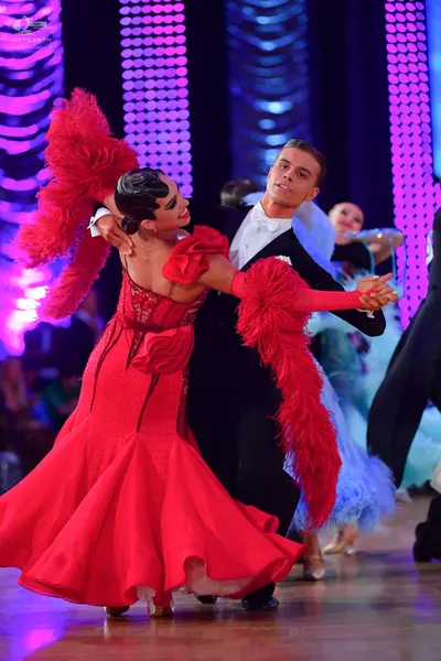 Dancesport competitor: Female dancer: red ballroom dress with large red feathery plumes on the arms and