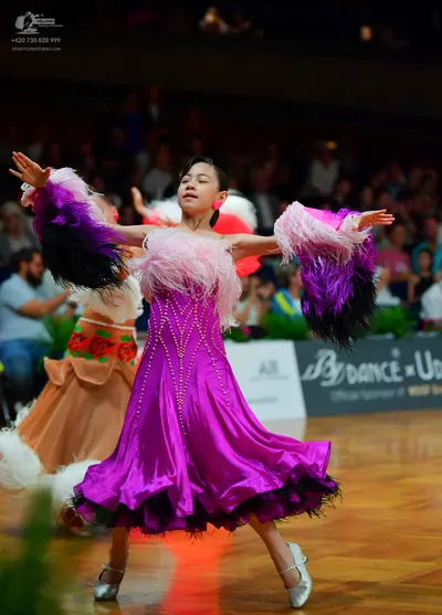 Dancesport competitor: Female dancer in foreground: purple Latin dress with rhinestone embellishments a