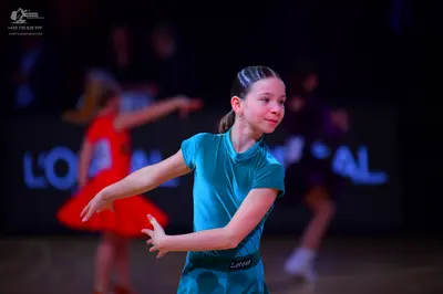 Dancesport competitor: Female dancer in foreground: teal short-sleeved Latin dress in a smooth, shiny f