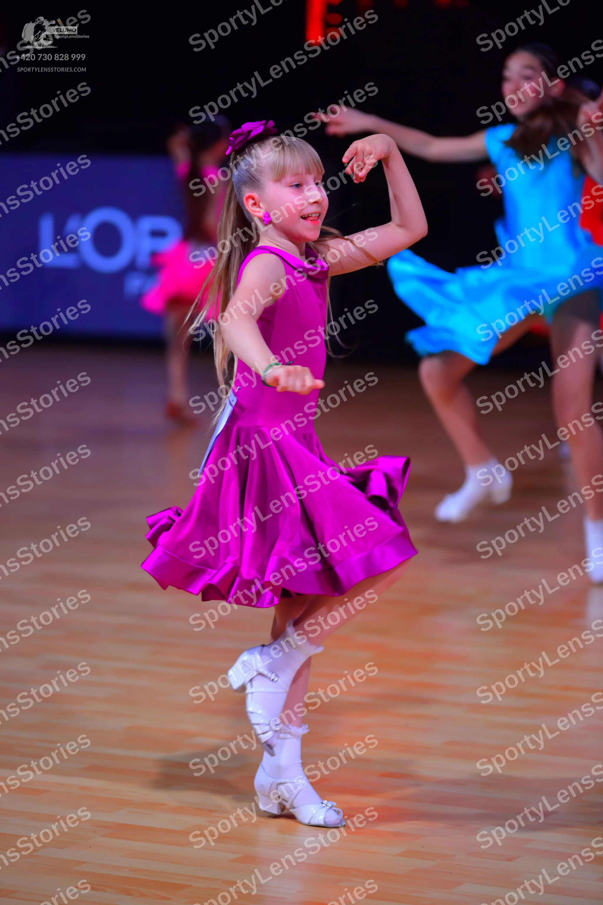 Dancesport competitor: Female dancer: magenta sleeveless latin dress with a flared skirt, made of satin