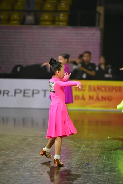 Dancesport competitor: Female dancer: bright pink latin dress with long sleeves and a flared skirt