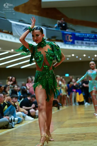Dancesport competitor: Female dancer in foreground: green latin dress with sequins and fringe