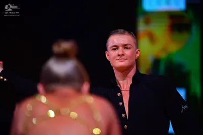 Dancesport competitor: Male dancer: black long-sleeved Latin dance shirt with gold metallic buttons