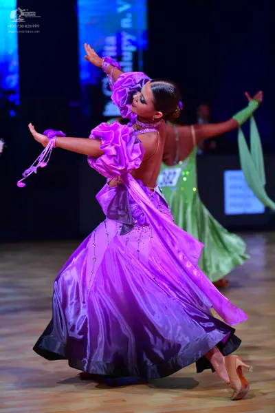 Dancesport competitor: Female dancer: a large, voluminous ballgown in shades of purple and lavender, fe