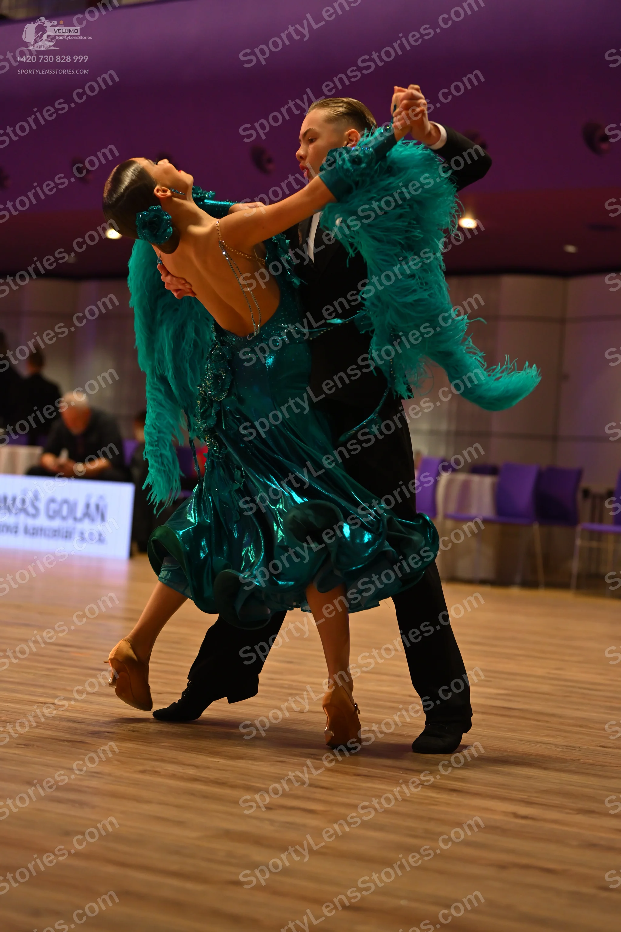 Dancesport competitor: Female dancer: teal Latin dance dress with ruffled skirt and feathered/fringed a