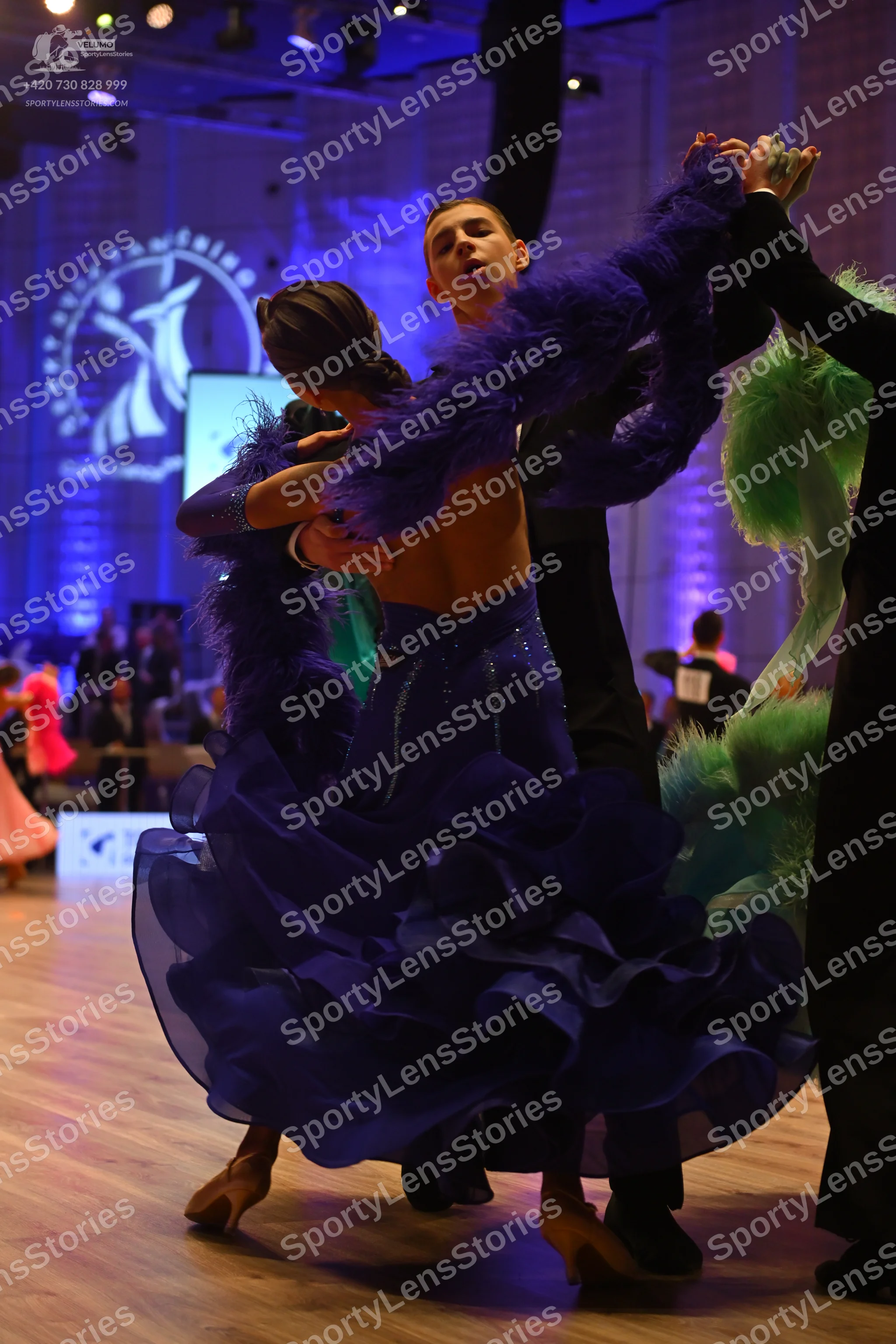 Dancesport competitor: Female dancer: navy blue ballgown with many layers of ruffled, sheer fabric and