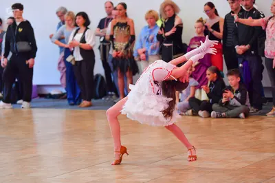 Dancesport competitor: Female dancer: white ruffled Latin dress with red/pink trim and long white glove