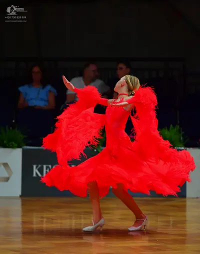 Dancesport competitor: Female dancer: red latin dress with long fringe sleeves and a wide fringed skirt
