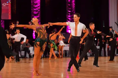 Dancesport competitor: Female dancer in foreground: dark green Latin dress with sequins and fringe