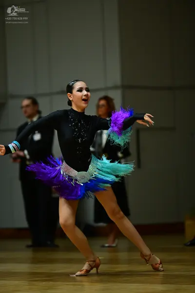 Dancesport competitor: Female dancer: black long-sleeved Latin bodysuit with a multi-colored (purple, b