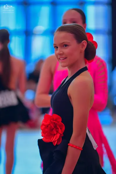Dancesport competitor: Female dancer in foreground: black halter-neck dress with a large red fabric flo