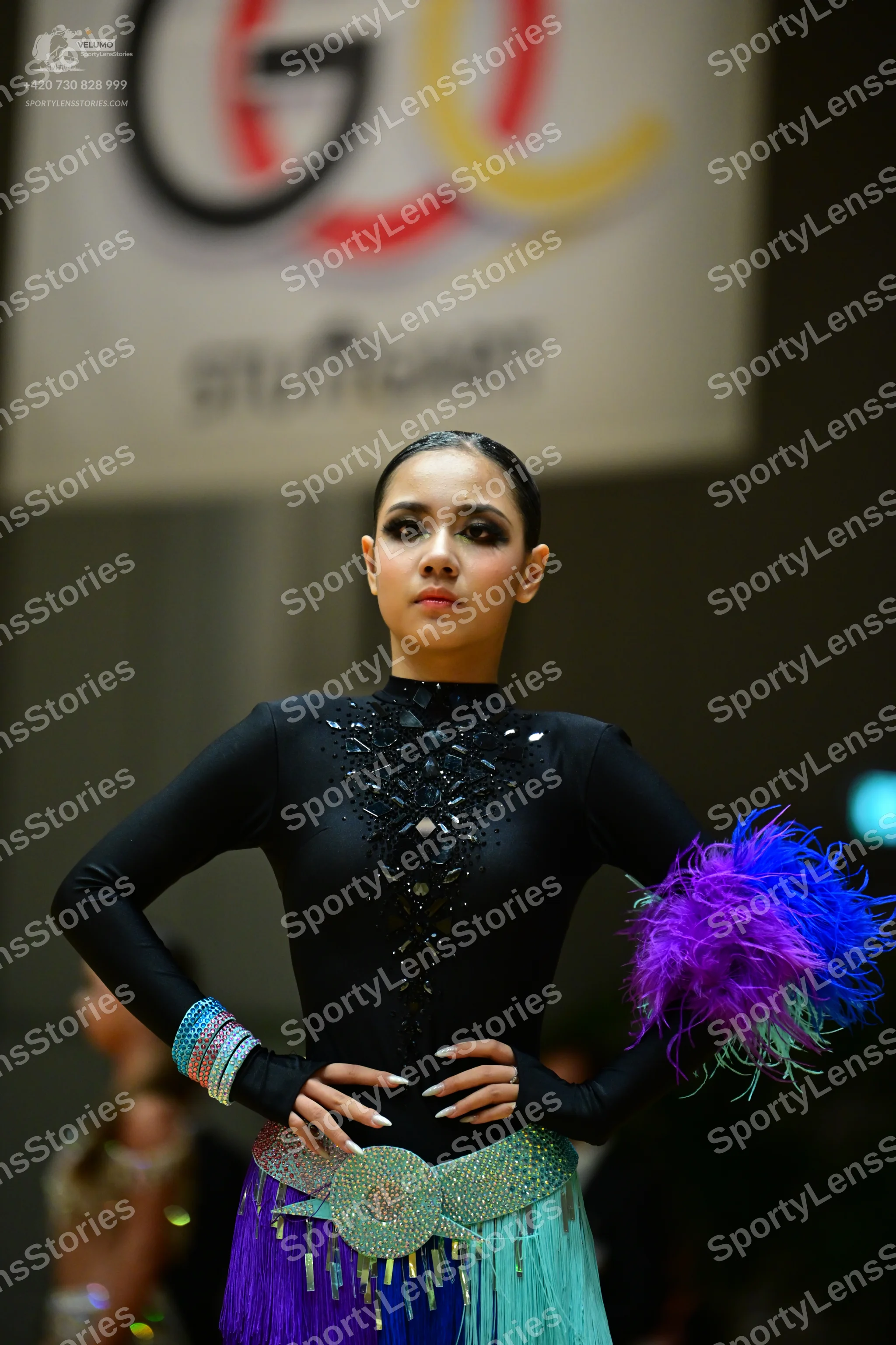 Dancesport competitor: Female dancer: black long-sleeved Latin top with black sequin embellishments, a