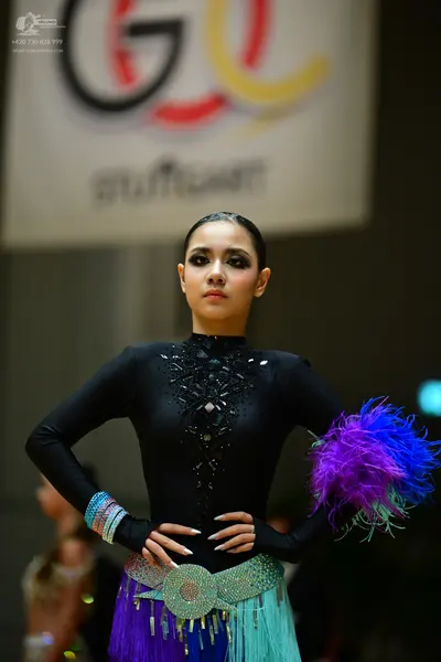 Dancesport competitor: Female dancer: black long-sleeved Latin top with black sequin embellishments, a 