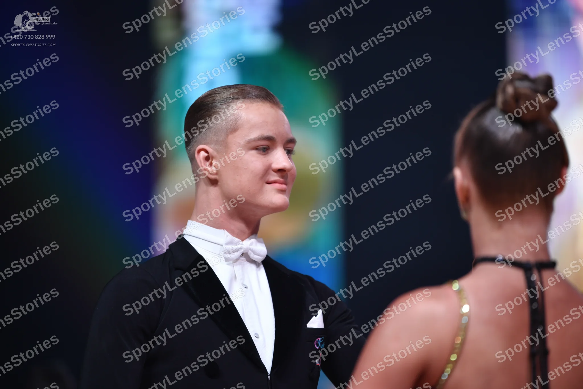 Dancesport competitor: Male dancer: black suit with a dark lapel, white shirt, white bow tie, and white
