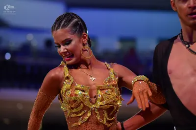Dancesport competitor: Female dancer: gold/bronze sequined Latin dress with a plunging neckline and lon