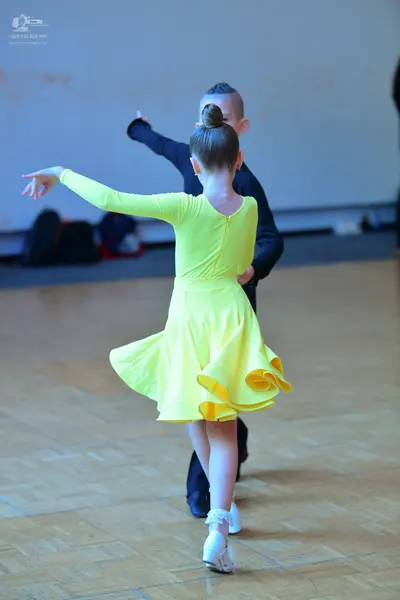 Dancesport competitor: Female dancer: bright yellow, long-sleeved dress with a flared, ruffled skirt