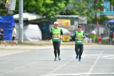 Marathon runner #5864, #5269: Runner 1: green jersey, black leggings, light-colored shoes, white cap