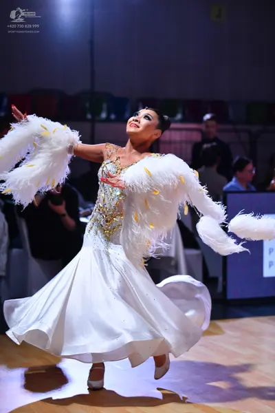 Dancesport competitor: Female dancer: white ballgown with a gold sequined bodice and large, voluminous 