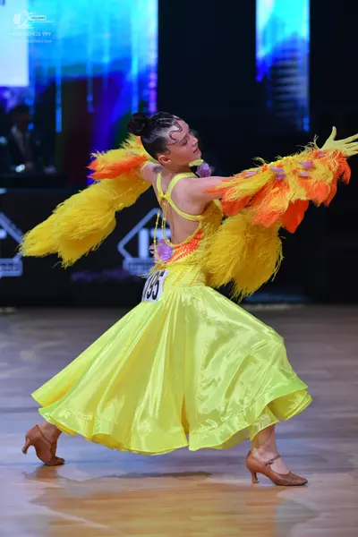 Dancesport competitor: Female dancer: bright yellow ballroom dress with large, voluminous yellow and or