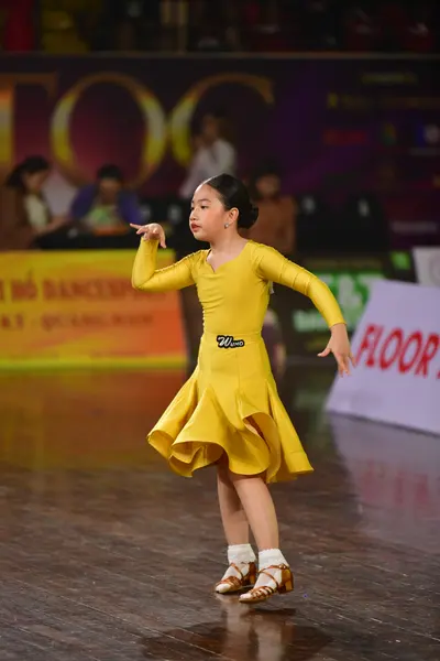 Dancesport competitor: Female dancer: yellow long-sleeved Latin dress with a flared skirt