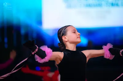 Dancesport competitor: Female dancer: black sleeveless Latin-style top with black gloves and light pink