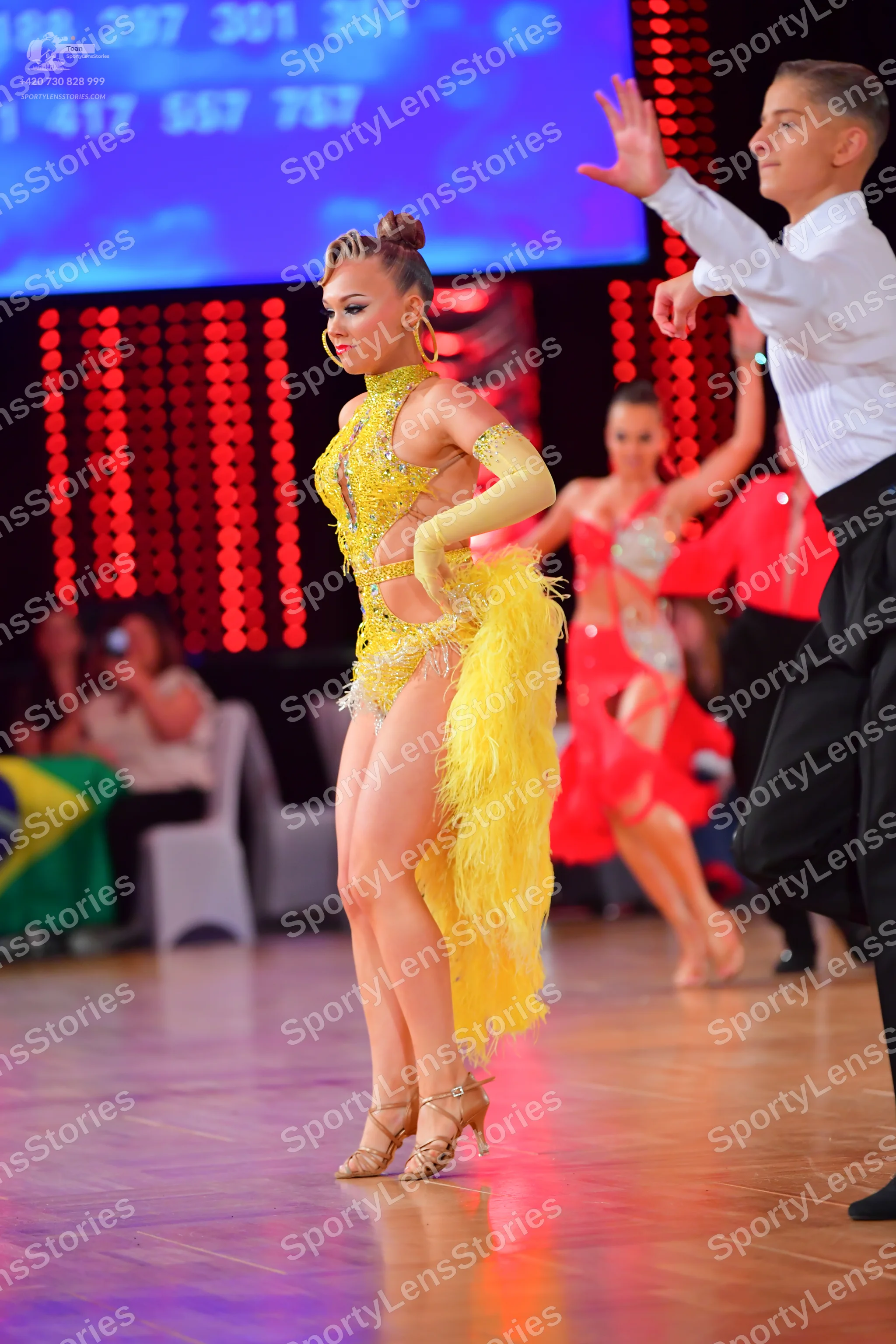 Dancesport competitor: Female dancer: yellow latin dress with sequins and long yellow fringe, matching