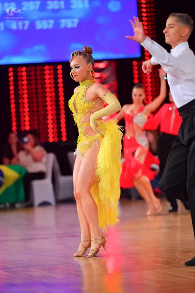 Dancesport competitor: Female dancer: yellow latin dress with sequins and long yellow fringe, matching 