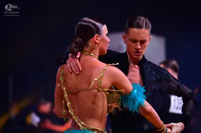 Dancesport competitor: Female dancer: backless Latin costume with gold sequined straps and turquoise/te