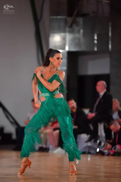 Dancesport competitor: Female dancer: emerald green Latin dance costume featuring long fringe, cutouts,