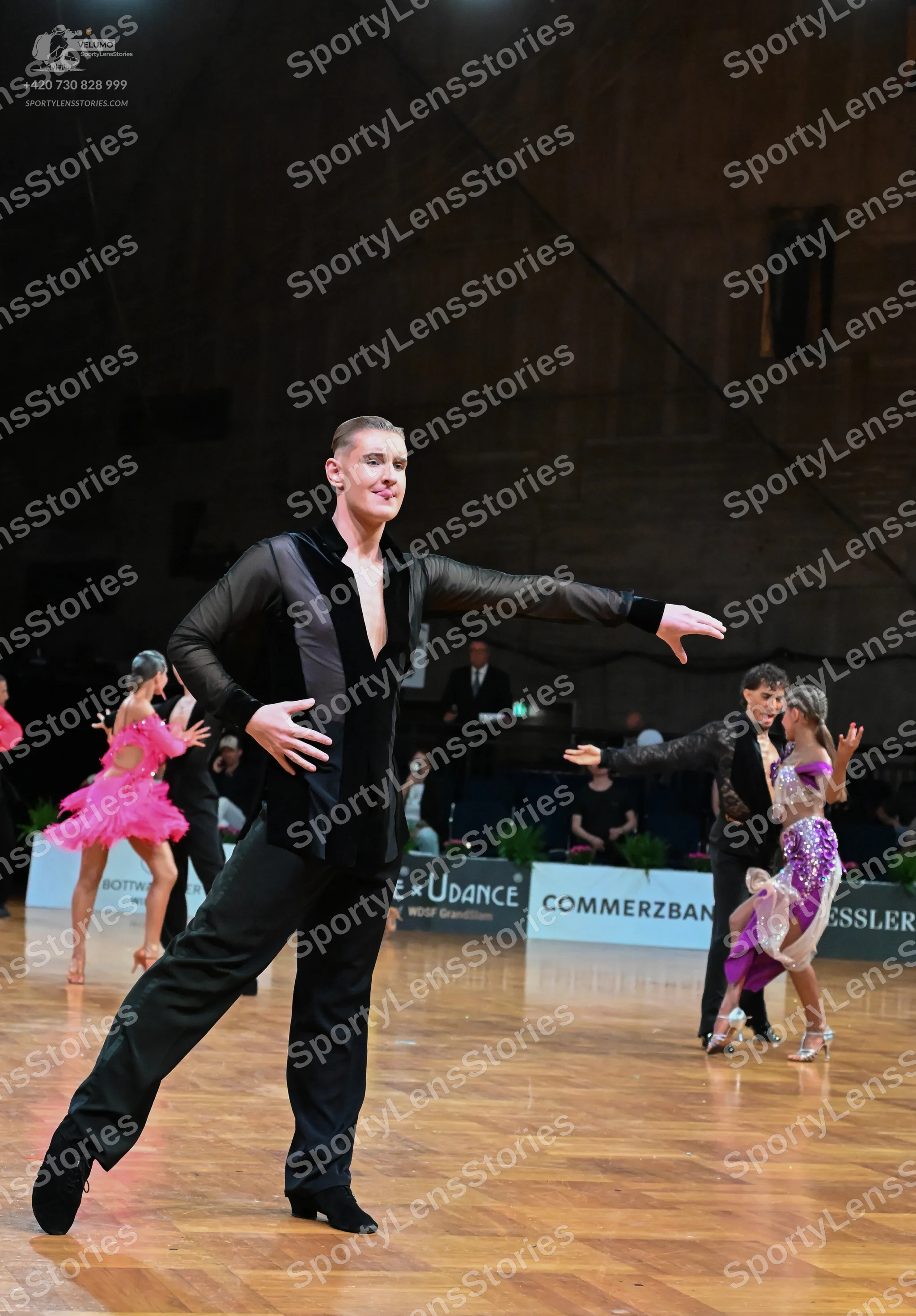Dancesport competitor: Male dancer (foreground): black suit jacket with deep V-neck and satin lapels, b
