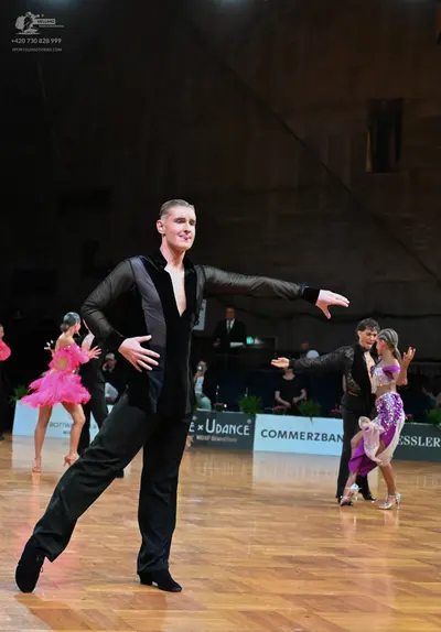 Dancesport competitor: Male dancer (foreground): black suit jacket with deep V-neck and satin lapels, b