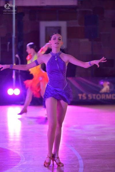Dancesport competitor: Female dancer (foreground): purple latin dance dress with rhinestones, halter ne