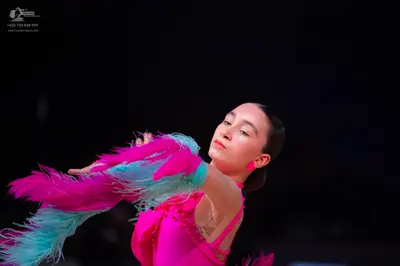 Dancesport competitor: Female dancer: bright pink/magenta Latin dress with long, flowing pink and light