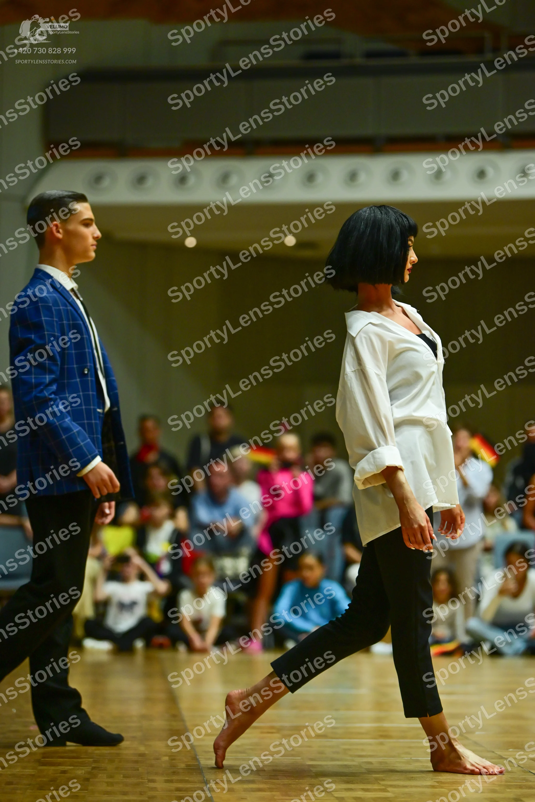 Dancesport competitor: Male dancer: blue windowpane patterned blazer, white shirt, dark tie, and black 