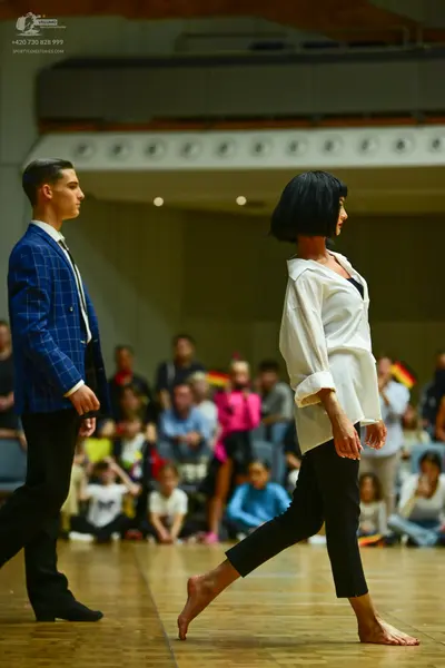 Dancesport competitor: Male dancer: blue windowpane patterned blazer, white shirt, dark tie, and black 