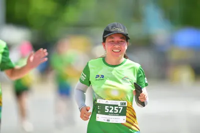 Marathon runner #5257: Runner 1: green jersey with yellow accents, black cap, black smartwatch