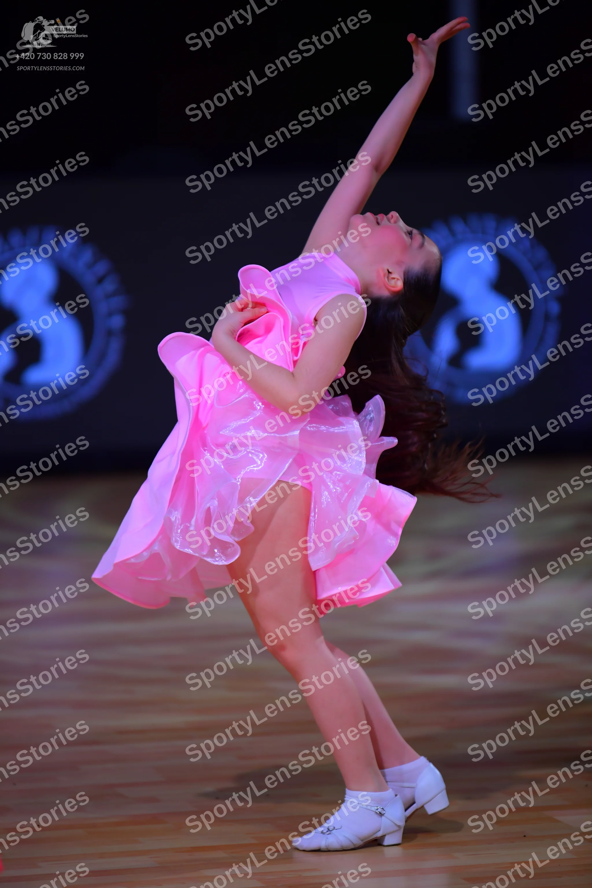 Dancesport competitor: Female dancer: bright pink latin dress with voluminous ruffled layers, likely ma