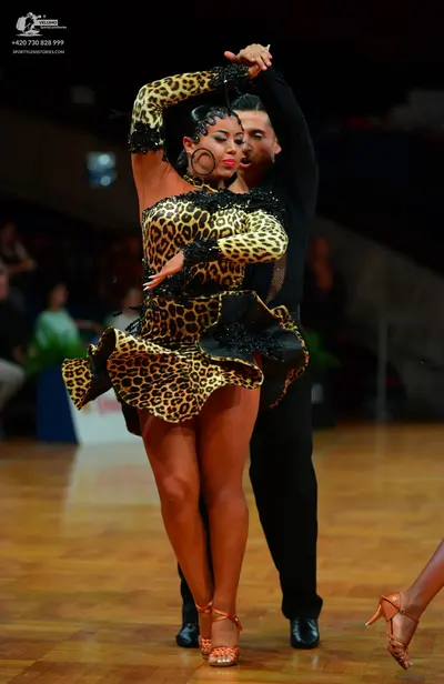 Dancesport competitor: Female dancer: leopard print Latin dress with long sleeves, a ruffled skirt, and
